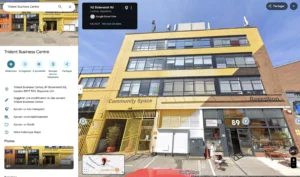 Vue extérieure d'un immeuble commercial jaune portant le nom Trident Business Centre et le numéro 89.