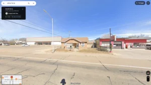 Vue à 360 degrés de bâtiments commerciaux le long d'une route asphaltée sous un ciel bleu.