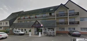 Vue d'ensemble d'un hôtel-restaurant double avec une aire de stationnement sur le devant.
