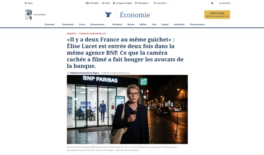 Une femme marchant la nuit devant une agence BNP Paribas allumée.