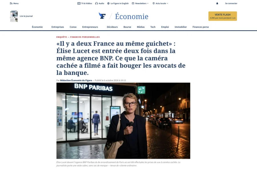 Une femme marchant la nuit devant une agence BNP Paribas allumée.